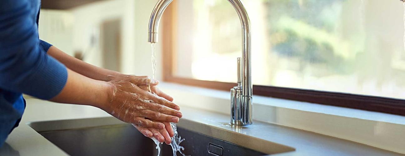 Woman washing her hands in her kitchen sink