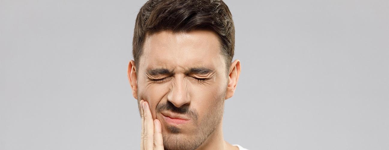 Man dealing with discomfort from senstive teeth. 