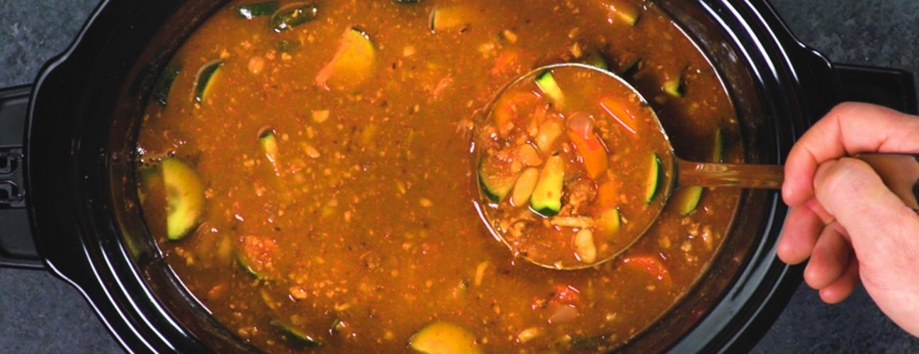 a person ladling turkey vegetable soup