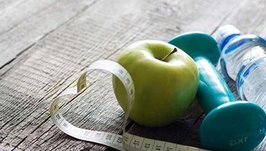 Water bottle, weight, measuring tape and apple on the floor