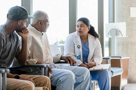Doctor speaking with an older patient and his adult son.